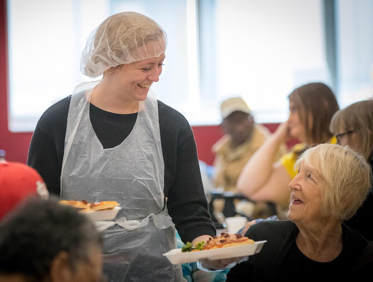A Creighton alumni serving food to the elderly