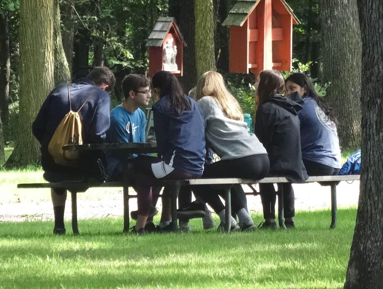Students sit at a picnic table during the Freshman Retreat