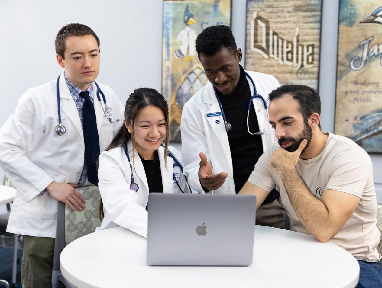 Four medical students at a table looking at laptop