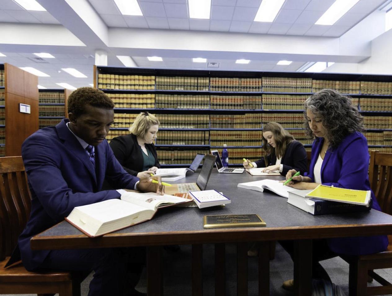 Four students at table and studying in Law Library